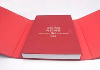 A linen red book is revealed inside the box
